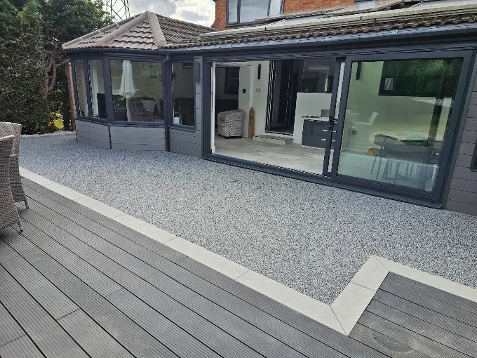Resin bound terrace beside grey composite decking outside bi-fold doors